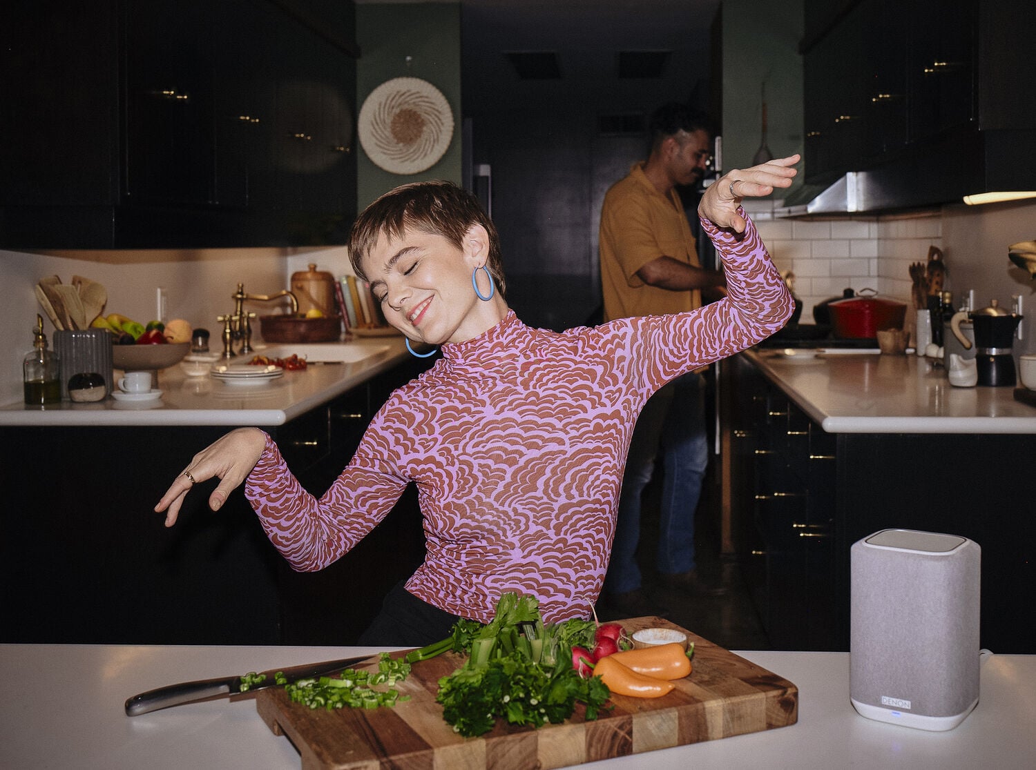 A woman dancing with a Denon Home speaker